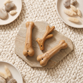 Load image into Gallery viewer, Titan chew shapes on a stone slab and cream wool rug seen from above