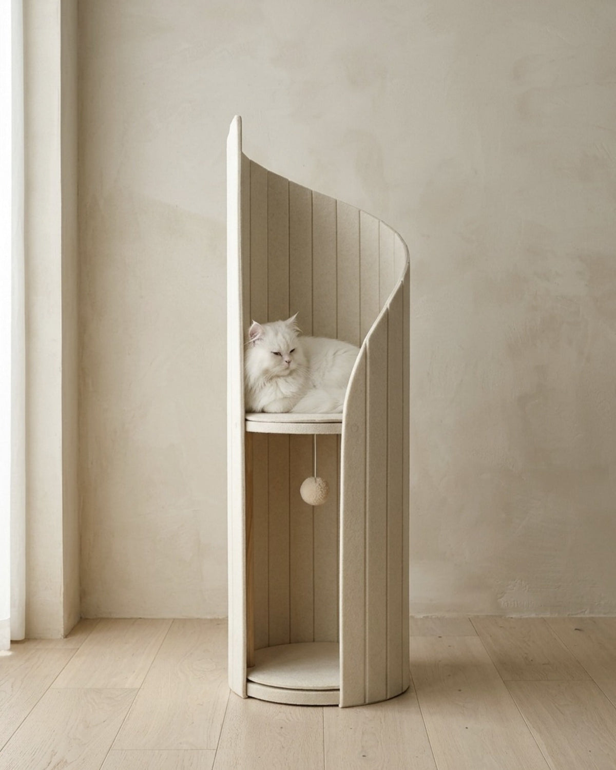 ARCHE in Cream in a plaster-walled room, a white long-haired cat resting on the upper perch, with the lower alcove and hanging pom-pom toy below