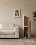 Load image into Gallery viewer, ARCHE in Cream beside a low linen sofa, showing its height against the furniture, with a white cat curled in the lower alcove
