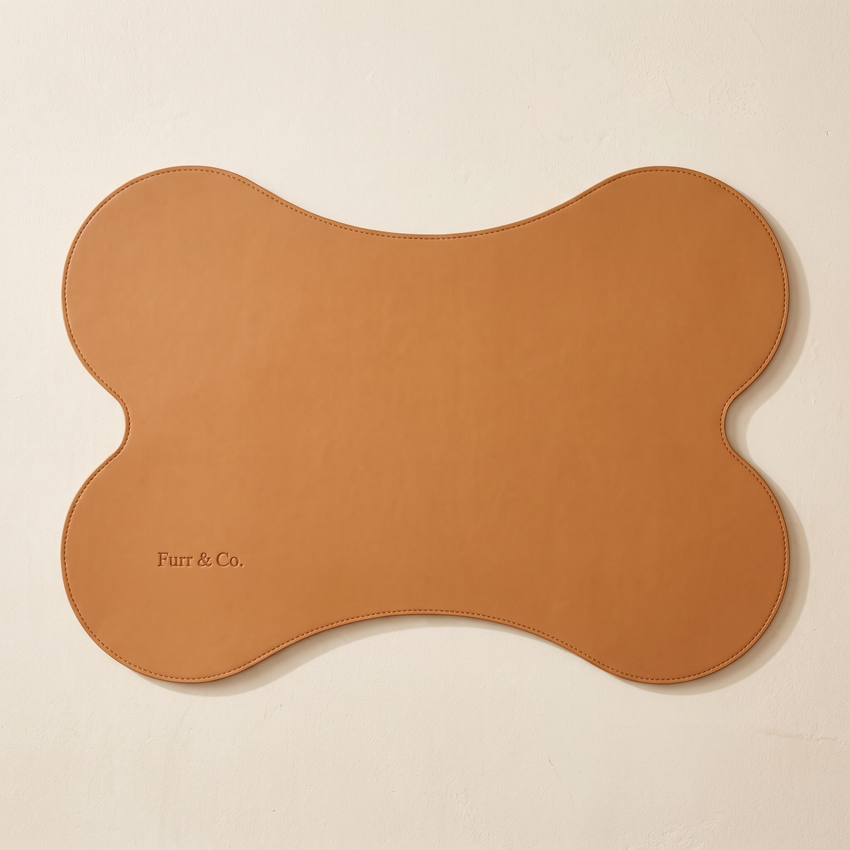 Beaumont Placemat seen from overhead, bone-shaped tan vegan leather with edge stitching