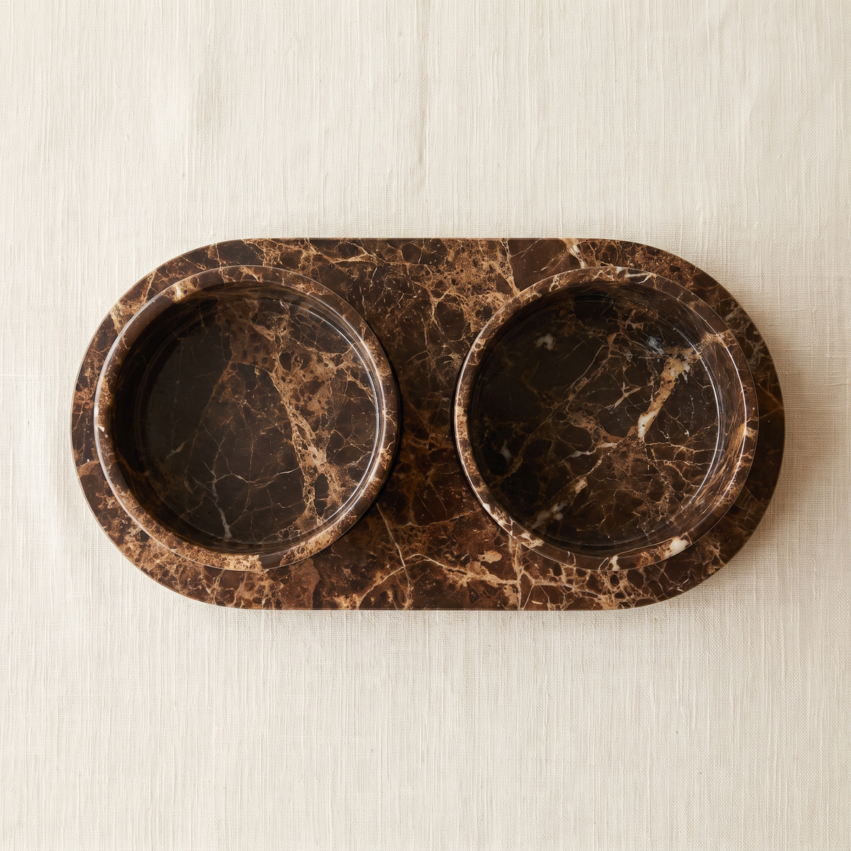 Castaño set from above: two round marble bowls seated in the oval tray